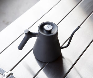 Bollitore nero opaco con collo d'oca sottile e termometro integrato, accessori per la preparazione, tutto sul caffè.