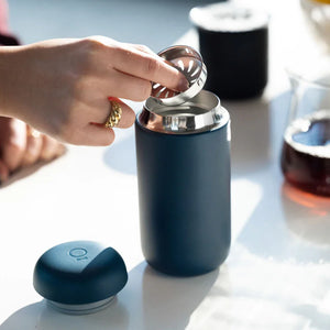Mano che inserisce un filtro in una tazza da caffè riutilizzabile blu opaco, parte di Take away ed EspressoGear, tutto sul caffè.