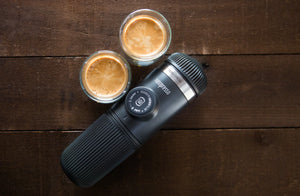 Macchina da espresso portatile con due tazze di espresso su superficie in legno, da macchine da caffè portatili e attrezzature per baristi