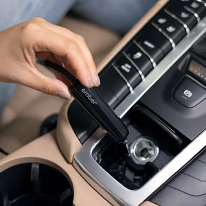 Mano che collega il caricabatterie per tazza elettrica Ember alla presa accendisigari dell'auto per una ricarica comoda.